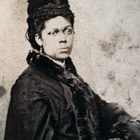 Photograph of Martha Bailey Briggs - she has her black hair in a braided updo, and is wearing a thick black dress