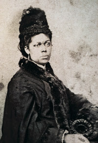 Photograph of Martha Bailey Briggs - she has her black hair in a braided updo, and is wearing a thick black dress