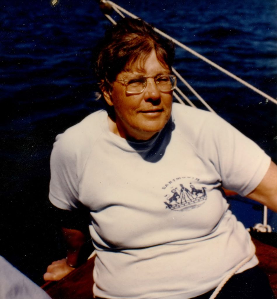 Photograph of Louise Strongman - she is sitting on a boat with short red hair, glasses, white shirt and shorts