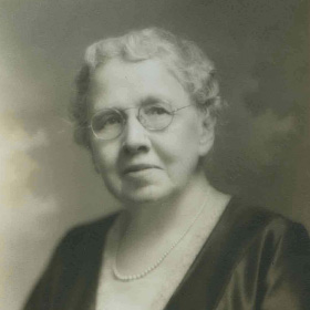 Photograph Of Miss Rebecca L. H. Taber - An Older Woman With Short Grey Hair, Round Glasses, And A Pearl Necklace