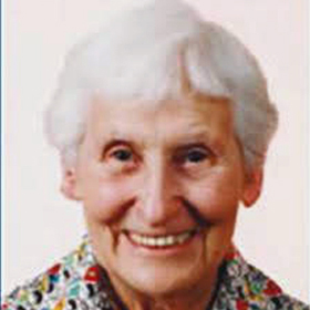 Photograph Of Eulalia Mendes -- Headshot Of Woman With Short White Hair Wearing A Colorful Collared Button-up Shirt.