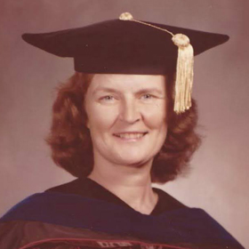 Photograph Of Elizabeth Atwood Lawrence A Woman In A Doctoral Graduation Robe, Hood, And Cap. She Has Red Hair In A Bob Cut And Is Smiling.