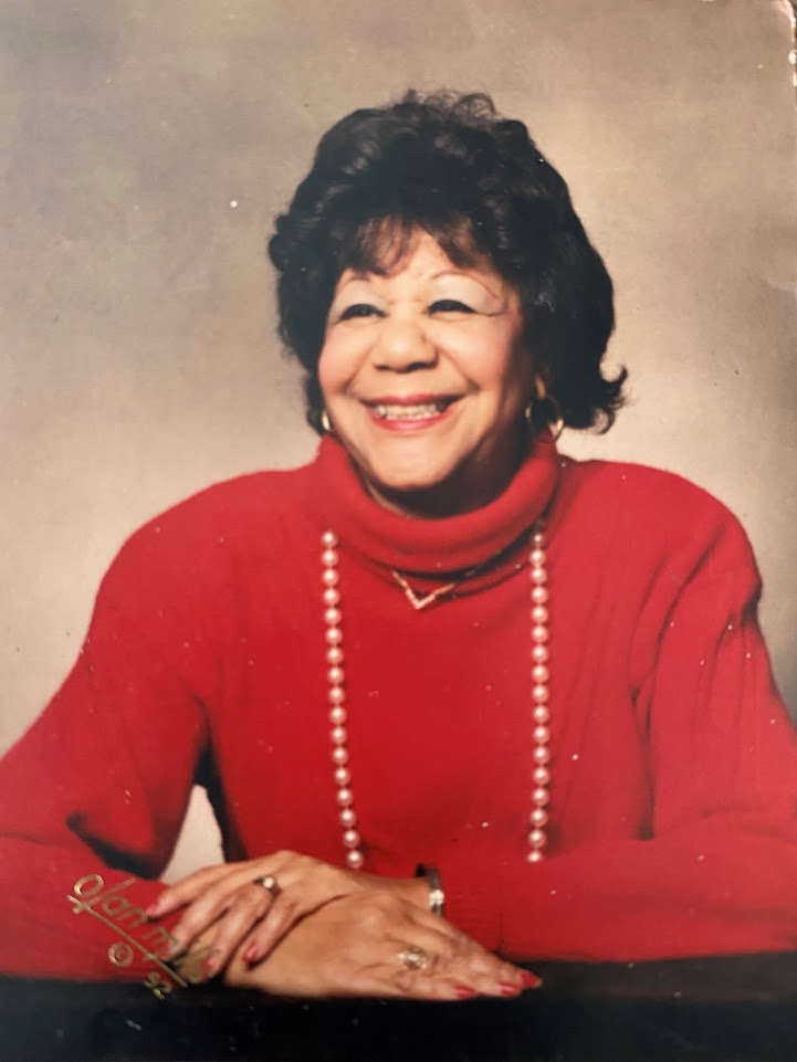 Photograph Of Zoe Alysse Washington Fabio - A Woman With Medium Length Black Hair, She Is Wearing A Red Sweater And A Pearl Necklace