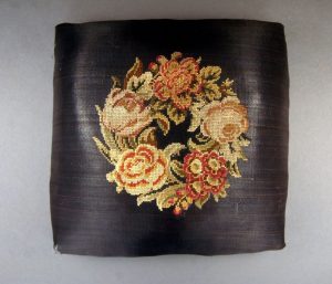A needlework flower wreath embroidered on a footstool