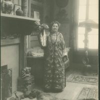 A Black And White Photograph Of Emily Noyes Vanderpoel Standing By A Fireplace Wearing A Kimono