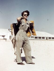 Photograph of Lillian Yonally wearing sunglasses and WASP uniform, holding gear