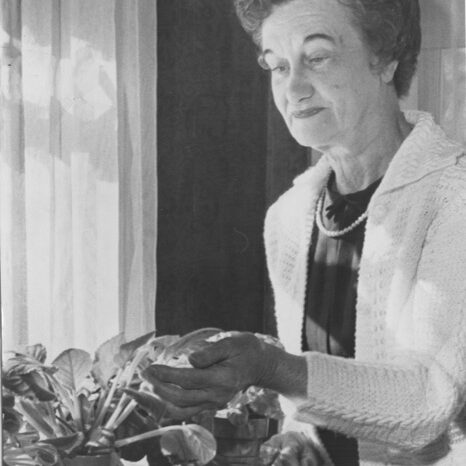 Photograph of Flora B. Peirce looking at plant